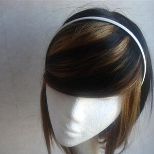 May include: A white plastic headband for hair. The headband is thin and smooth.