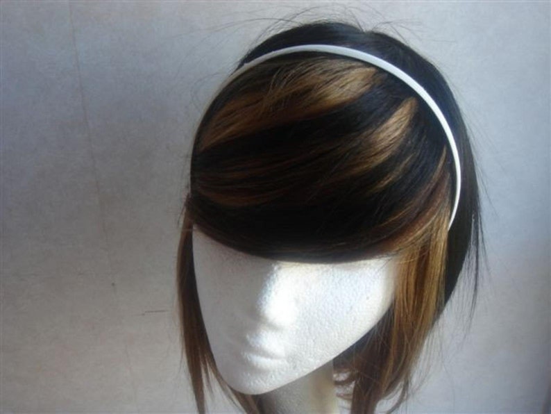 May include: A white plastic headband for hair. The headband is thin and smooth.