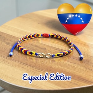 May include: A woven bracelet with blue, yellow, and red threads, featuring an infinity charm. The bracelet is displayed on a wooden surface, with a heart-shaped decoration in the background, colored like the Venezuelan flag. The text "Especial Edition" is below the bracelet.