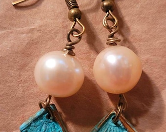 May include: A pair of earrings with a white pearl and a turquoise blue square pendant. The earrings are made with brass wire and have a hook closure.