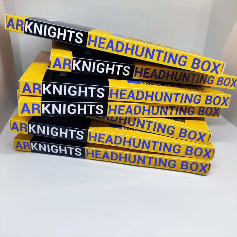 May include: A stack of yellow boxes with the text "ARKNIGHTS HEADHUNTING BOX" in white and blue. The boxes have a black stripe across the top. The boxes are stacked on top of each other.