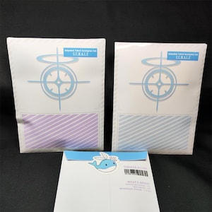 May include: Two white envelopes with blue and white striped patterns and a blue circle with a cross inside. The envelopes have the text "Integrated Federal Investigation Unit SCHALE" printed on them. The envelopes are sitting on a white surface with a blue whale sticker and a white card with the text "@MAER.COM WHAT'S INSIDE: ACRYLIC KEYCHAIN BUTTON PIN WATERPROOF STICKER - 1 EA" printed on it.
