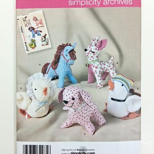 May include: A Simplicity Archives sewing pattern envelope 2763 for stuffed animals. The front shows five plush toys: a blue gingham horse, a cherry-print deer, a pink patterned dog, a white chick with lace, and a white duck with a striped hat.