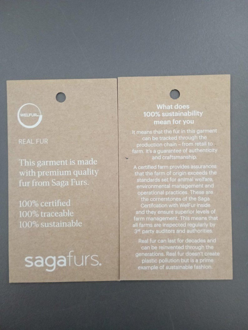 Puede incluir: Dos etiquetas de papel marr&oacute;n con texto blanco. La etiqueta de la izquierda dice "REAL FUR" y "This garment is made with premium quality fur from Saga Furs." La etiqueta de la derecha dice "What does 100% sustainability mean for you?" y explica que la piel es rastreable desde la granja hasta la venta al por menor y es una garant&iacute;a de autenticidad y artesan&iacute;a. Ambas etiquetas tienen el logotipo "WELFUR" y el texto "sagafurs."