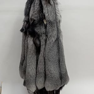 Puede incluir: Un manojo de pieles de zorro plateado colgando de un gancho. La piel es suave y esponjosa, de color gris plateado.