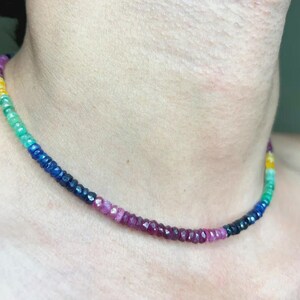 May include: A multi-colored gemstone necklace. The necklace features a gradient of colors, including yellow, green, blue, and shades of purple and red. The gemstones are small and evenly spaced, creating a vibrant and eye-catching accessory.