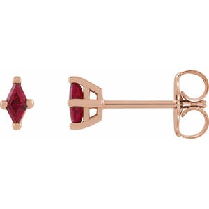 May include: A pair of rose gold stud earrings with a red gemstone in a square shape.