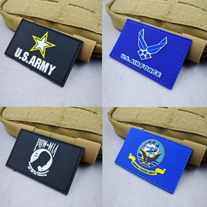 May include: Four military patches are displayed. The U.S. Army patch is black with a yellow star and white text. The U.S. Air Force patch is blue with a white emblem and text. A black POW-MIA patch and a blue U.S. Navy patch are also shown.