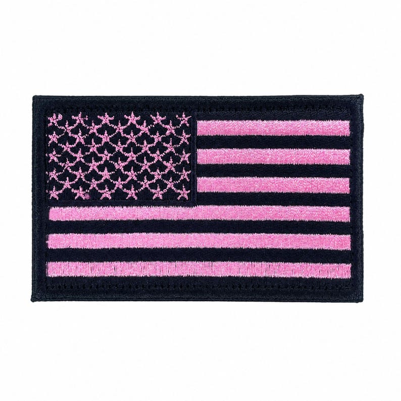 May include: A rectangular embroidered patch featuring a stylized American flag design. The canton displays pink embroidered stars on a black background, while the field consists of alternating horizontal pink and black embroidered stripes.
