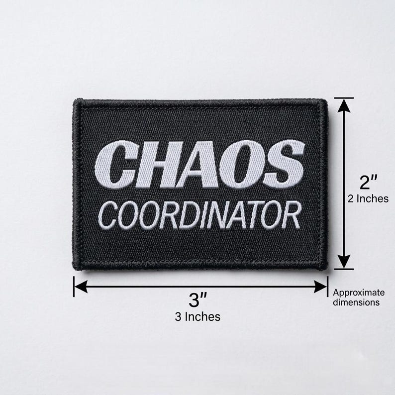 Pode incluir: Um patch retangular preto com texto bordado branco que diz "CHAOS COORDINATOR". O patch tem aproximadamente 7,6 cm de largura e 5,1 cm de altura.
