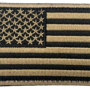 May include: A rectangular embroidered patch featuring a stylized United States flag design. The pattern consists of alternating horizontal black and tan stripes, with a field of tan stars on a black background in the upper left corner.