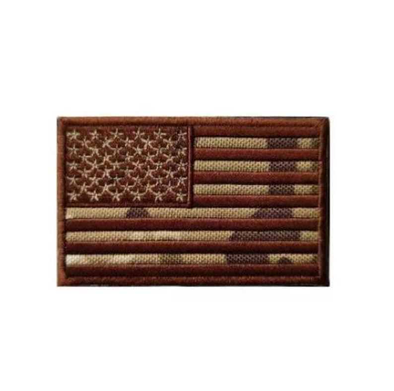 May include: A rectangular embroidered patch featuring the United States flag in a monochromatic brown and tan color scheme. The design includes the traditional stars and stripes pattern with a textured, woven appearance and a stitched border.