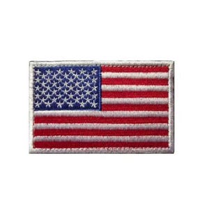 May include: A rectangular embroidered patch featuring the flag of the United States of America. The design includes a blue canton with white stars on the left and alternating horizontal red and white stripes across the rest of the fabric surface.