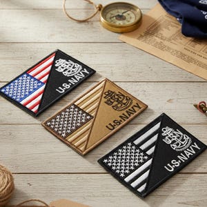 May include: Three rectangular U.S. Navy patches with a flag design. One patch is black with a white and red flag, another is tan with a brown flag, and the third is black with a white flag. Each patch has the words "U.S. NAVY" and an anchor emblem.