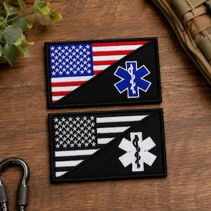 May include: Two rectangular embroidered patches featuring a diagonal split design. The top patch displays the American flag in red, white, and blue, paired with a blue Star of Life symbol. The bottom patch features a black and white flag with a white Star of Life.