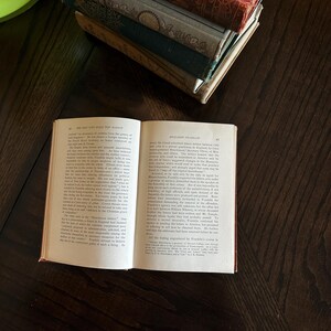 May include: An open book with a brown leather cover. The book is titled "The Rise and Fall of the Nation" and "Benjamin Franklin". The text on the pages discusses the history of the American Revolution.