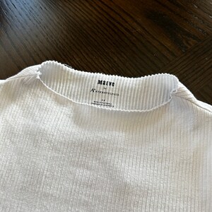 K&ouml;nnte beinhalten: Wei&szlig;es, geripptes Langarmshirt mit einem schwarzen Etikett mit der Aufschrift "Maeve by Anthropologie" und "Gr&ouml;&szlig;e S".