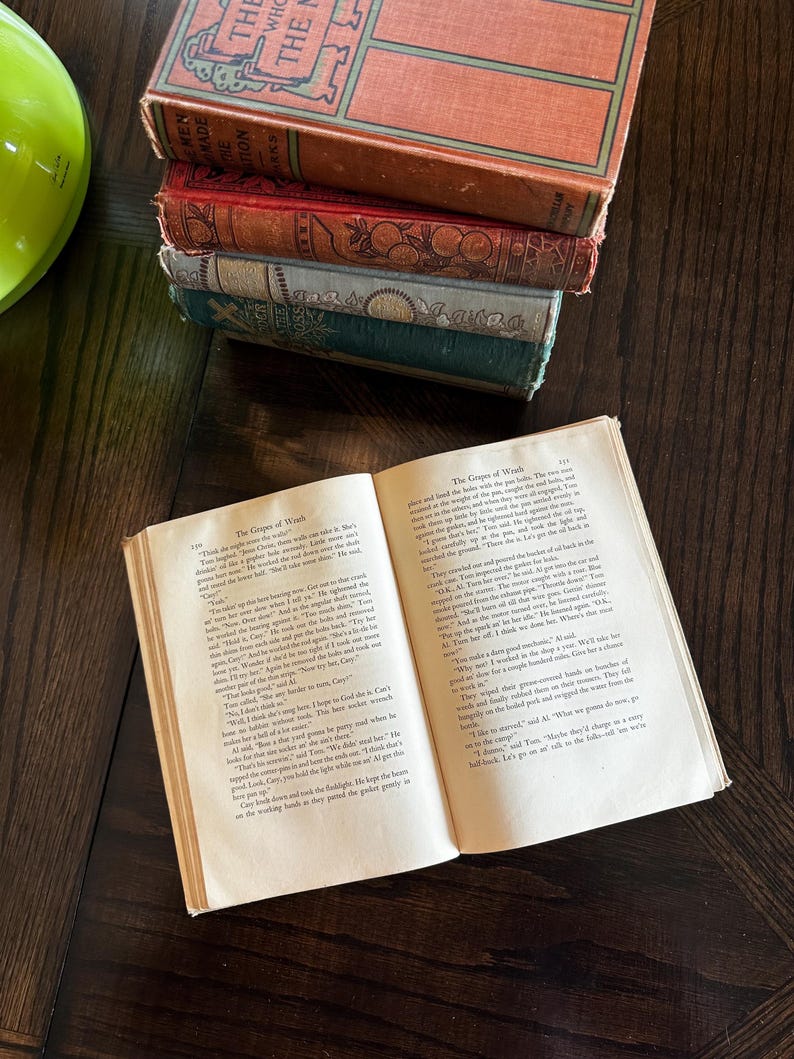 May include: An open book with the title "The Grapes of Wrath" on the cover. The book is open to a page with text about a man named "Cary".