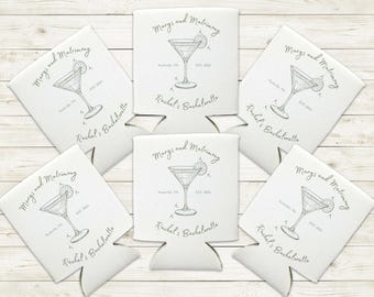 May include: Six white can coolers with a silver design of a martini glass with a lime wedge. The text on the coolers reads "Margs and Matrimony" and "Rachel's Bachelorette".