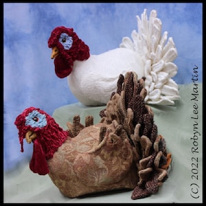 May include: Two handmade fabric turkeys, one with a white body and white feathery tail, the other with a brown and gold body and a brown feathery tail. Both turkeys have red velvet heads with blue accents.