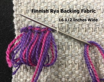 May include: Close-up of Finnish Rya backing fabric with a needle and colorful yarn. The text "Finnish Rya Backing Fabric 16 1/2 Inches Wide" is visible. The yarn is purple and pink, and the fabric is a neutral gray.