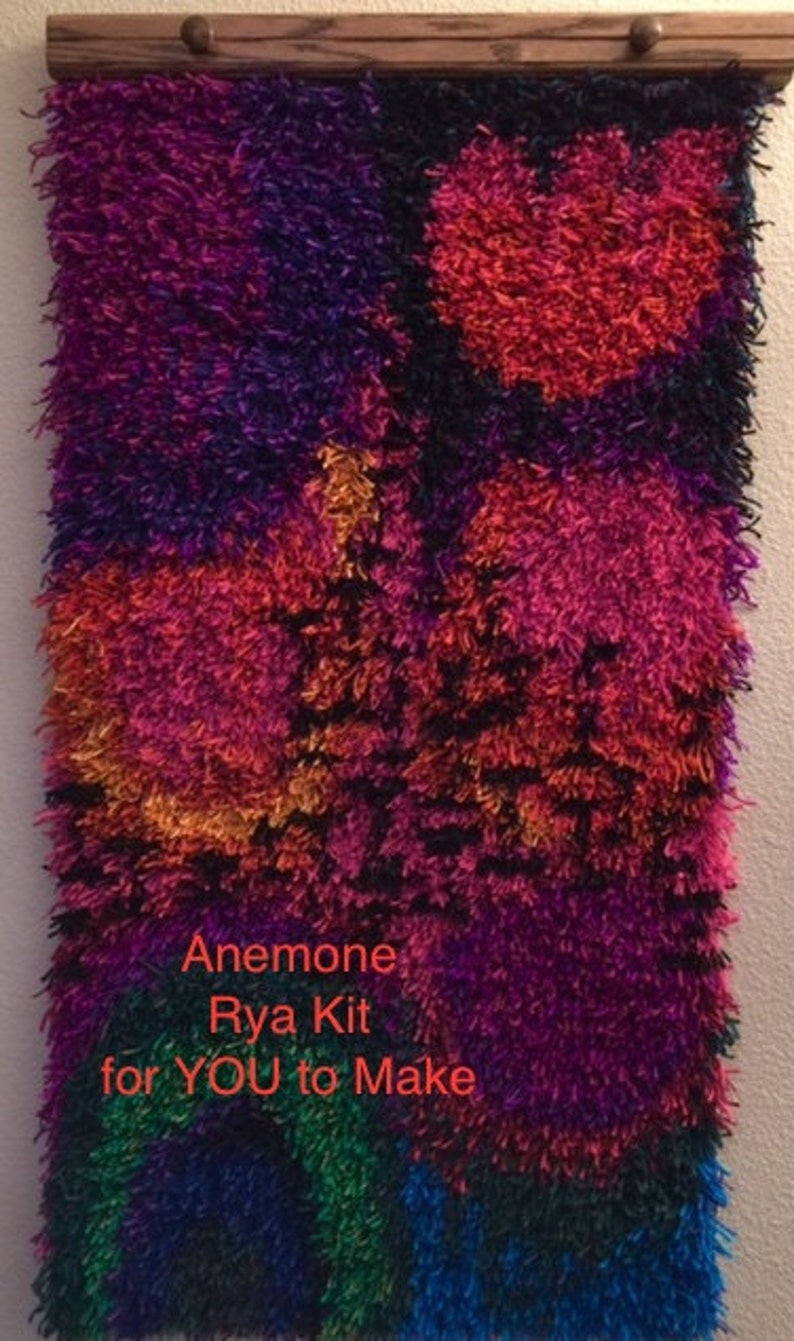 May include: A colorful, textured wall hanging with a wooden rod at the top. The design features a mix of vibrant colors including red, purple, orange, and blue. The text "Anemone Rya Kit for YOU to Make" is visible.
