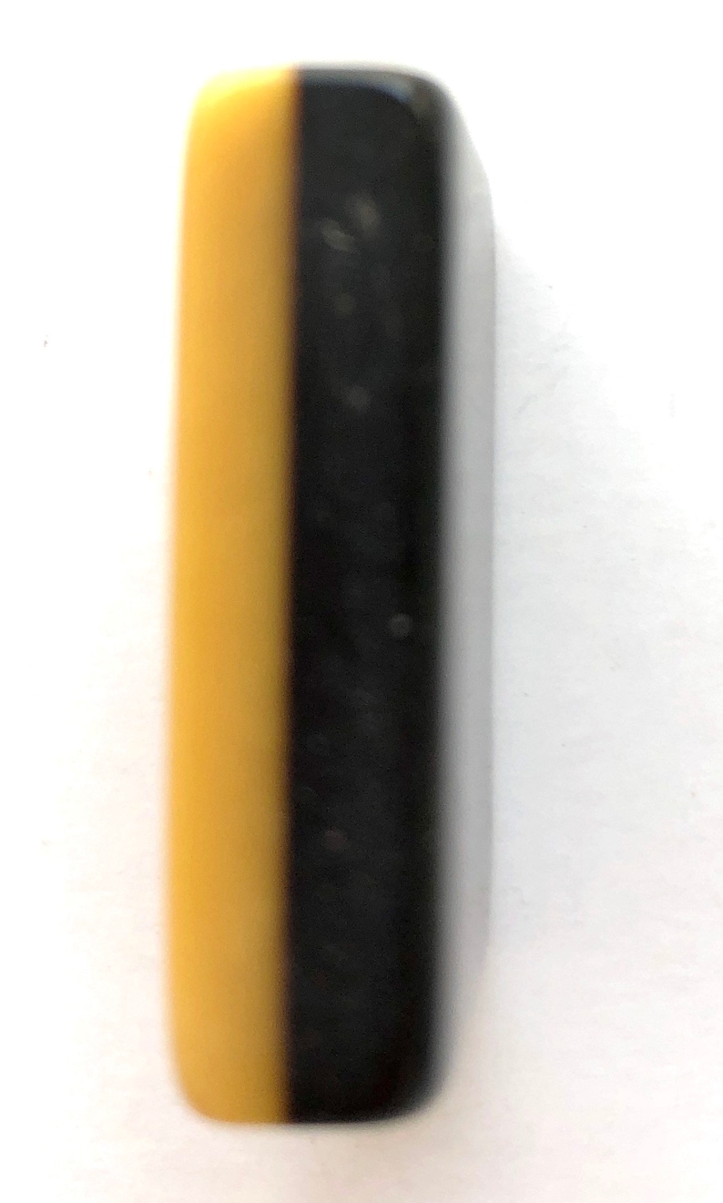 May include: A rectangular object, bisected vertically, with a yellow-tan color on the left and black on the right. The object has rounded edges and a smooth, glossy finish. The item is set against a white background.