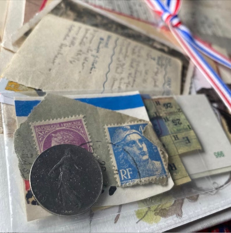 May include: A close-up of a collection of vintage French stamps and a coin. The stamps are blue and purple and feature images of a woman and a soldier. The coin is silver and features a woman's profile.