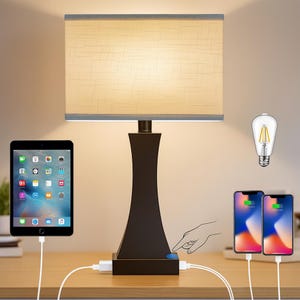May include: A brown table lamp with a rectangular beige lampshade and a dark brown base. The lamp has a USB charging port and is shown with a tablet and two phones charging. An Edison-style lightbulb is also visible.