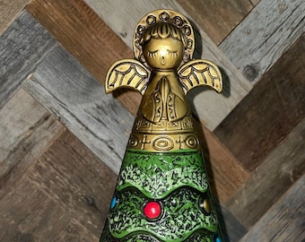 May include: A green ceramic Christmas tree ornament with a gold angel on top. The tree is decorated with red, blue, and gold ornaments.