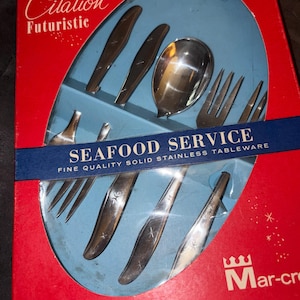 May include: Vintage "Citation Futuristic" seafood service set in its original box. The set includes forks, spoons, and knives made of stainless steel. The box is red with a blue interior and features the text "SEAFOOD SERVICE".