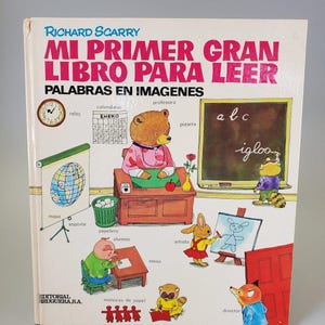 May include: A vintage children's book titled "MI PRIMER GRAN LIBRO PARA LEER" by Richard Scarry. The cover features colorful illustrations of animals in a classroom setting, including a bear teacher, a rabbit artist, and a pig student.