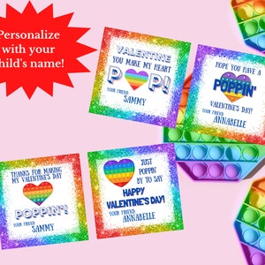 Op de afbeelding: Vier printbare Valentijnsdagkaarten met een regenboog pop-it speelgoedontwerp. De kaarten hebben glitterachtergronden en zeggen "Valentine you make my heart pop!"  "Hope you have a poppin' Valentine's Day!"  "Thanks for making my Valentine's Day poppin'" en "Just poppin' by to say Happy Valentine's Day!"