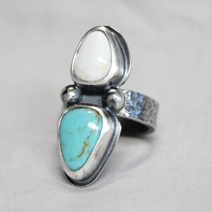 May include: A silver ring with a turquoise and white stone setting. The ring band is textured and has a hammered finish.