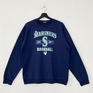 May include: Navy blue Mariners baseball sweatshirt with the team's logo and the text "MARINERS BASEBALL EST. 1977" in white and teal. The sweatshirt has long sleeves and a crew neck, and is hanging on a black hanger.