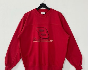 May include: A red sweatshirt with the number "8" and "EARNHARDT JR" printed in black. The sweatshirt has a crew neck and long sleeves with ribbed cuffs. The garment is hanging on a black hanger against a white background.