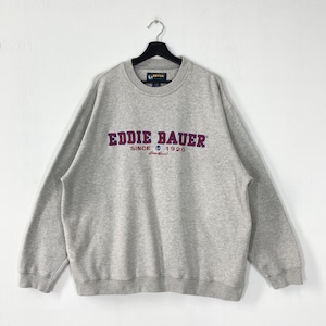 May include: A light gray Eddie Bauer sweatshirt with a crew neck, hanging on a black hanger. The sweatshirt features the brand name in a purple and red embroidered design, with "SINCE 1920" below. The sweatshirt is made of a soft, comfortable material.