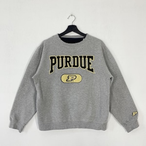 May include: A gray Purdue University sweatshirt with the word "PURDUE" in black and gold lettering across the chest. Below the word is a gold oval with a black "P" inside. A smaller "P" is on the right sleeve.