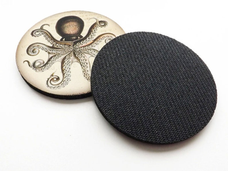 May include: A round coaster with a vintage illustration of an octopus on a white background. The back of the coaster is black.