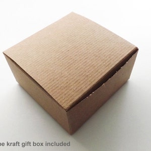 May include: A brown pinstripe kraft gift box. The box is square and has a textured surface.
