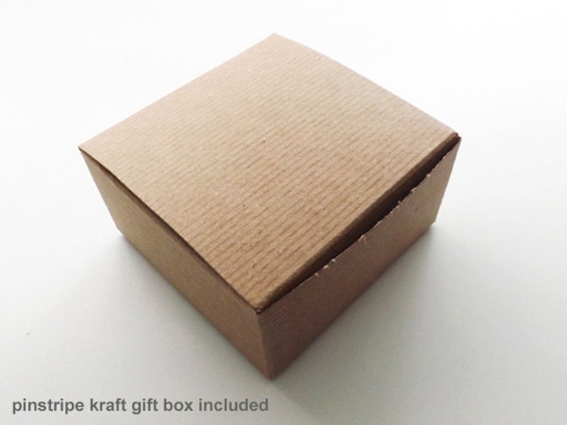 May include: A brown pinstripe kraft gift box. The box is square and has a textured surface.