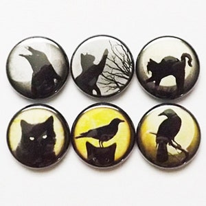 May include: Six round black and white buttons with images of black cats and crows. The buttons have a glossy finish.
