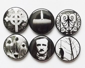 May include: Set of six black and white button pins with various gothic and spooky imagery. The pins feature a Celtic cross, a candle, a gate, a raven, a tree, and a portrait of Edgar Allan Poe.