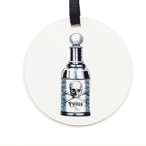 May include: A white round ceramic ornament with a black ribbon hanger. The ornament features a black and white illustration of a glass bottle with a skull and crossbones and the word "Poison" printed on the label.