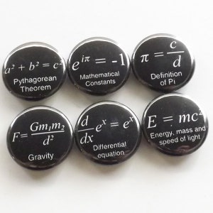 May include: Six black button pins with white text featuring different mathematical formulas and equations. The formulas include the Pythagorean theorem, Euler's identity, the definition of pi, Newton's law of universal gravitation, the differential equation, and Einstein's famous equation for energy, mass, and the speed of light.