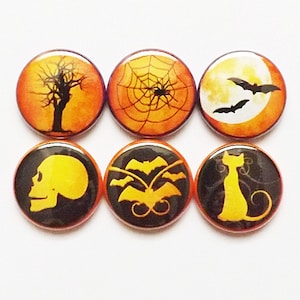 May include: Six round Halloween themed buttons with orange and black colors. The buttons feature a skull, a spider web, a cat, a tree, bats, and a moon.