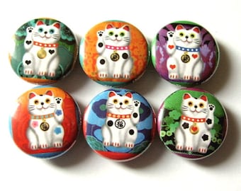 May include: Six round button pins featuring a white Maneki-Neko, or lucky cat, with black spots and a gold coin. Each pin has a different colorful background with floral and geometric patterns.