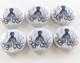 May include: Six white round buttons with a black and white illustration of an octopus on each button. The octopus is facing forward with its tentacles spread out.