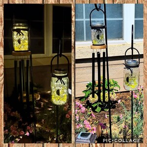 May include: Two solar-powered mason jar wind chimes with a sunflower design and the text "Wherever life plants you, bloom with grace." The jars are lit up with white lights and are hanging from black metal stands.
