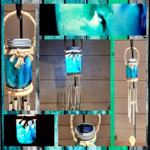 May include: A teal blue glass jar wind chime with a solar powered light inside. The jar is decorated with a swirl of teal blue paint and has a brown rope handle. The wind chime is made of metal tubes and has a leaf-shaped charm at the bottom.